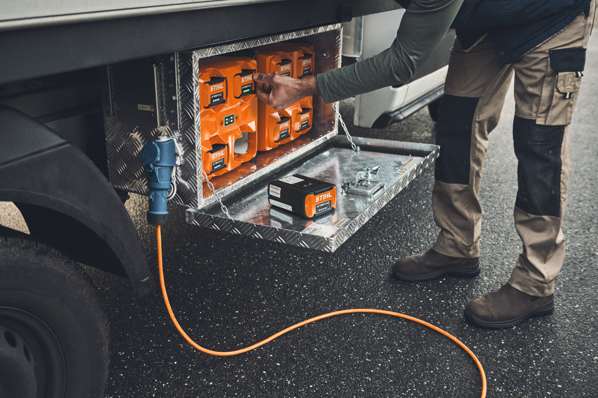 A man takes a charged STIHL AP 500 battery out of the charging box